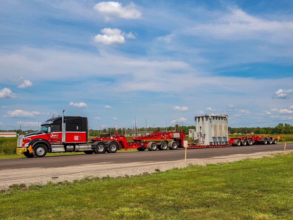 Scott-Woods heavy haul fleet transporting an oversized transformer using specialized multi-axle trailer equipment.